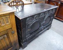 AN ANTIQUE PROFUSELY CARVED BLACK OAK CHEST WITH PLAIN LIFT UP TOP, ARCH CARVED TWO PANEL FRONT (3'