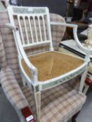 AN ANTIQUE WHITE PAINTED AND DECORATED TUB SHAPED OPEN ARMCHAIR, WITH RAIL BACK, CANE PANEL SEAT, ON