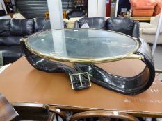 A MODERNIST COFFEE OR CENTRE TABLE WITH GILT BRASS FRAMED GLASS OVAL TOP, IN IRREGULAR BLACK PLASTIC