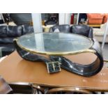 A MODERNIST COFFEE OR CENTRE TABLE WITH GILT BRASS FRAMED GLASS OVAL TOP, IN IRREGULAR BLACK PLASTIC