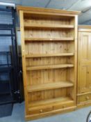 A GOOD QUALITY LARGE PINE OPEN BOOKCASE WITH FIVE ADJUSTABLE SHELVES AND TWO SMALL DRAWERS BELOW,