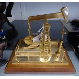 A CLOCKWORK BRASS MODEL OF AN OIL WELL PUMP, ON OBLONG BASE