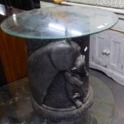 A LAMP TABLE, WITH CIRCULAR GLASS TOP, ON BLACK FIBREGLASS DRUM SHAPED BASE, EMBOSSED IN HIGH RELIEF