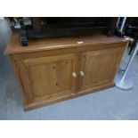 A LOW TWO DOOR PINE CUPBOARD