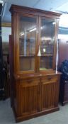 A CIRCA 1900 WALNUTWOOD BOOKCASE, THE UPPER SECTION HAVING TWO GLAZED DOORS, THE BASE HAVING TWO