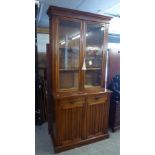 A CIRCA 1900 WALNUTWOOD BOOKCASE, THE UPPER SECTION HAVING TWO GLAZED DOORS, THE BASE HAVING TWO