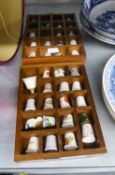 COLLECTION OF 31 CERAMIC THIMBLES ON TWO WALL RACKS