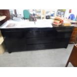 A BLACK GLOSS 'NEWTON' SIDEBOARD WITH THREE CENTRAL DRAWERS, FLANKED BY TWO END CUPBOARDS, ON PLINTH
