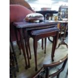 A NEST OF THREE REPRODUCTION MAHOGANY COFFEE TABLES WITH GLASS INSET TOPS AND A SMALL CIRCULAR STOOL