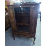 A CARVED OAK  SINGLE GLAZED DOOR DISPLAY CABINET, WITH SINGLE DRAWER BELOW, RAISED ON CABRIOLE