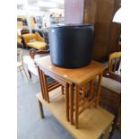 A NEST OF THREE TEAK WOOD OBLONG COFFEE TABLES AND A BLACK VINYL DRUM SHAPED POUFFE