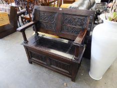 AN INTER-WAR YEARS OAK MONKS BENCH, WITH LINEN-FOLD PANELS TO THE BOX BASE