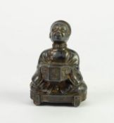 CHINESE WHITE METAL FIGURAL MATCH HOLDER, modelled as a seated attendant holding a hexagonal vase,