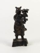 ANTIQUE CHINESE PATINATED BRONZE FIGURAL CANDLESTICK, modelled as a robed figure holding a floral