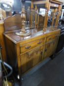 A 1920's/30's OAK SIDEBOARD, TWO DRAWERS OVER TWO CUPBOARDS, HAVING A LOW BACK WITH CENTRAL CIRCULAR