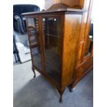 AN EARLY TWENTIETH CENTURY OAK TWO GLASS PANELLED DOOR DISPLAY CABINET ON CABRIOLE SUPPORTS