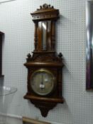 A GOOD QUALITY OAK CASED ANEROID BAROMETER WITH COLUMN DECORATION