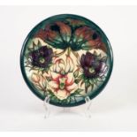 MODERN MOORCROFT TUBE LINED POTTERY PLATE, painted in colours and decorated with three flowers, on a