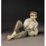 ROYAL COPENHAGEN CHINA FIGURE, painted in muted tones and modelled as a reclining man eating, (865),