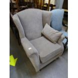 A GOOD QUALITY GREY WINGED BACK ARMCHAIR, RAISED ON TURNED FRONT SUPPORTS WITH CHROME CASTORS