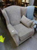 A GOOD QUALITY GREY WINGED BACK ARMCHAIR, RAISED ON TURNED FRONT SUPPORTS WITH CHROME CASTORS