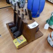 A WOODEN PIPE RACK WITH SIX BRIAR PIPES AND TWO EBONY ROLLER RULERS