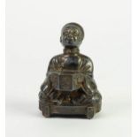 CHINESE WHITE METAL FIGURAL MATCH HOLDER, modelled as a seated attendant holding a hexagonal vase,