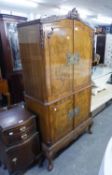 A CARVED WALNUTWOOD COCKTAIL CABINET, HAVING FOUR DOORS, THE UPPER SECTION FITTED WITH GLASS SHELVES