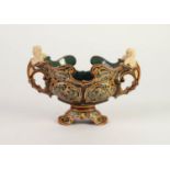 PROBABLY METTLACH MOULDED POTTERY TWO HANDLED PEDESTAL BOWL, of boat form with winged cherub