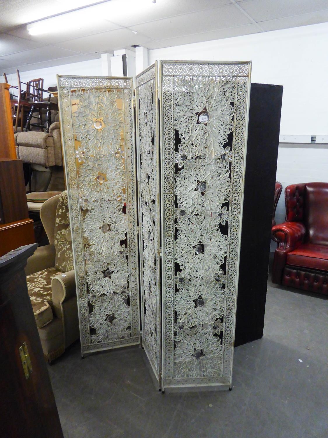 A THREE FOLD ORNATE METAL PRIVACY SCREEN DECORATED WITH FIVE LARGE FLOWERS TO EACH PANEL (173cm)