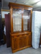 A REPRODUCTION YEW-WOOD LIBRARY BOOKCASE, THE UPPER SECTION HAVING TWO GLAZED DOORS, ABOVE TWO