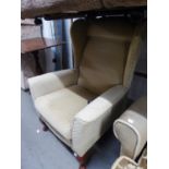 A WINGED BACK EASY ARMCHAIR, COVERED IN BEIGE FABRIC