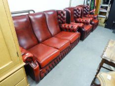 A WINGED LOUNGE SUITE OF THREE PIECES, BUTTON UPHOLSTERED IN OXBLOOD HIDE,  VIZ A THREE SEATER