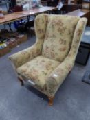 A GOOD QUALITY WINGED FIRESIDE ARMCHAIR, COVERED IN FLORAL FABRIC AND RAISED ON CABRIOLE LEGS