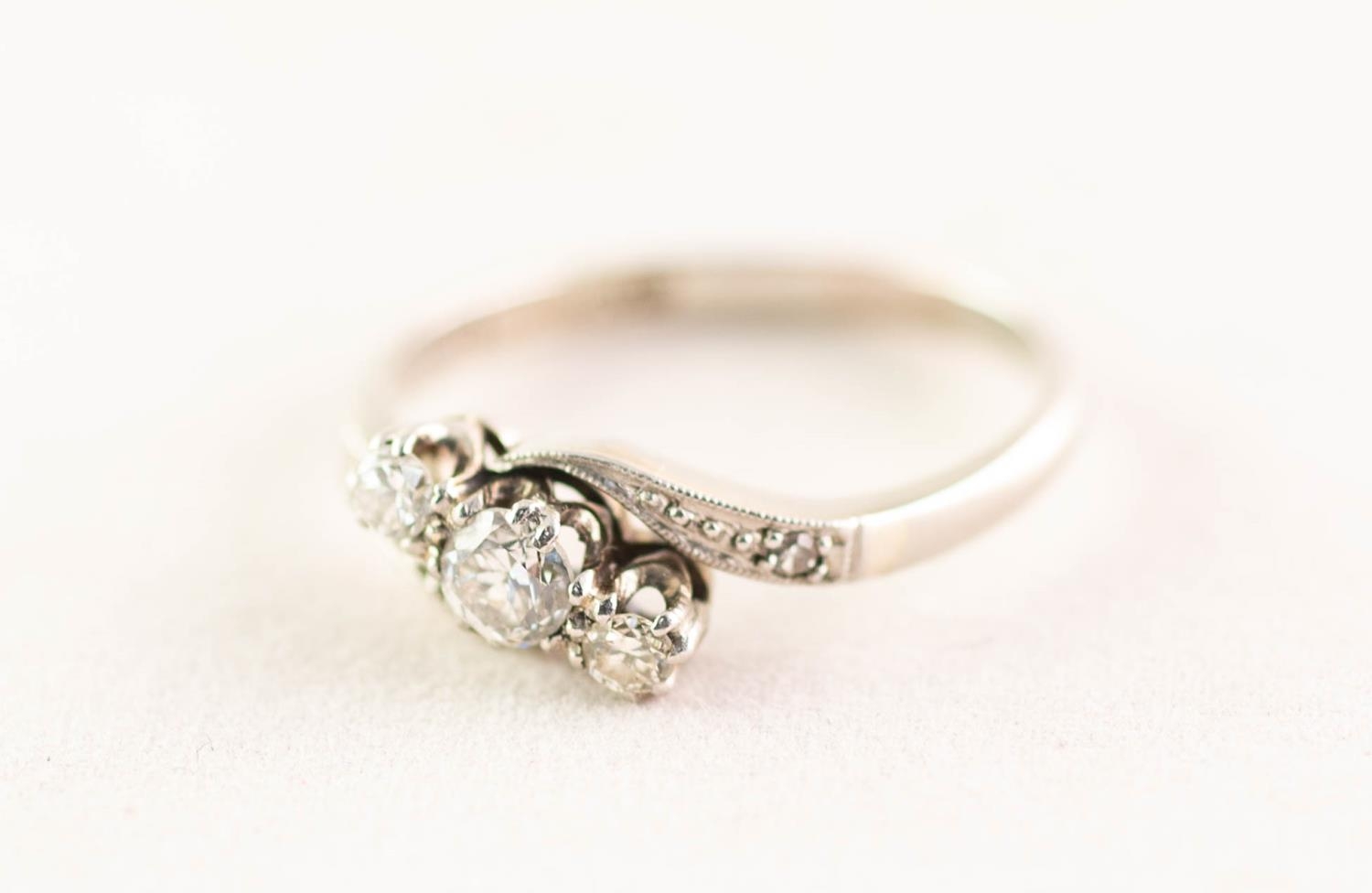 18ct WHITE GOLD AND PLATINUM CROSSOVER RING set with three round brilliant cut diamonds and a tiny