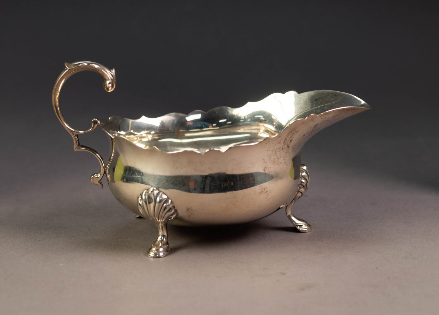 GEORGIAN STYLE SILVER SAUCE BOAT, with cyma edges, acanthus free scroll handle , on three shell
