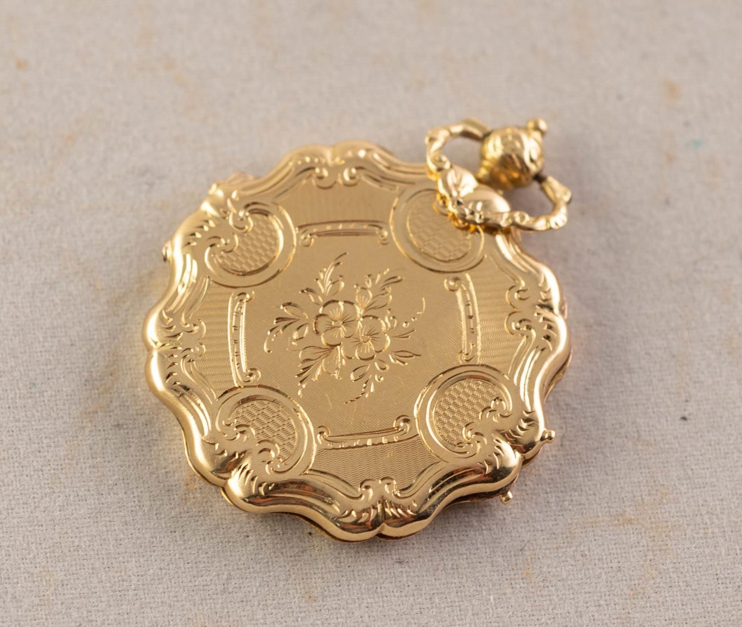 VICTORIAN FLORAL ENGRAVED AND ENGINE TURNED GOLD COLOURED METAL SHAPED CIRCULAR PENDANT, with rococo