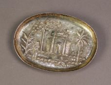 ASIAN EMBOSSED SILVER COLOURED METAL OVAL, SHALLOW DISH, decorated with a temple, figure and palm