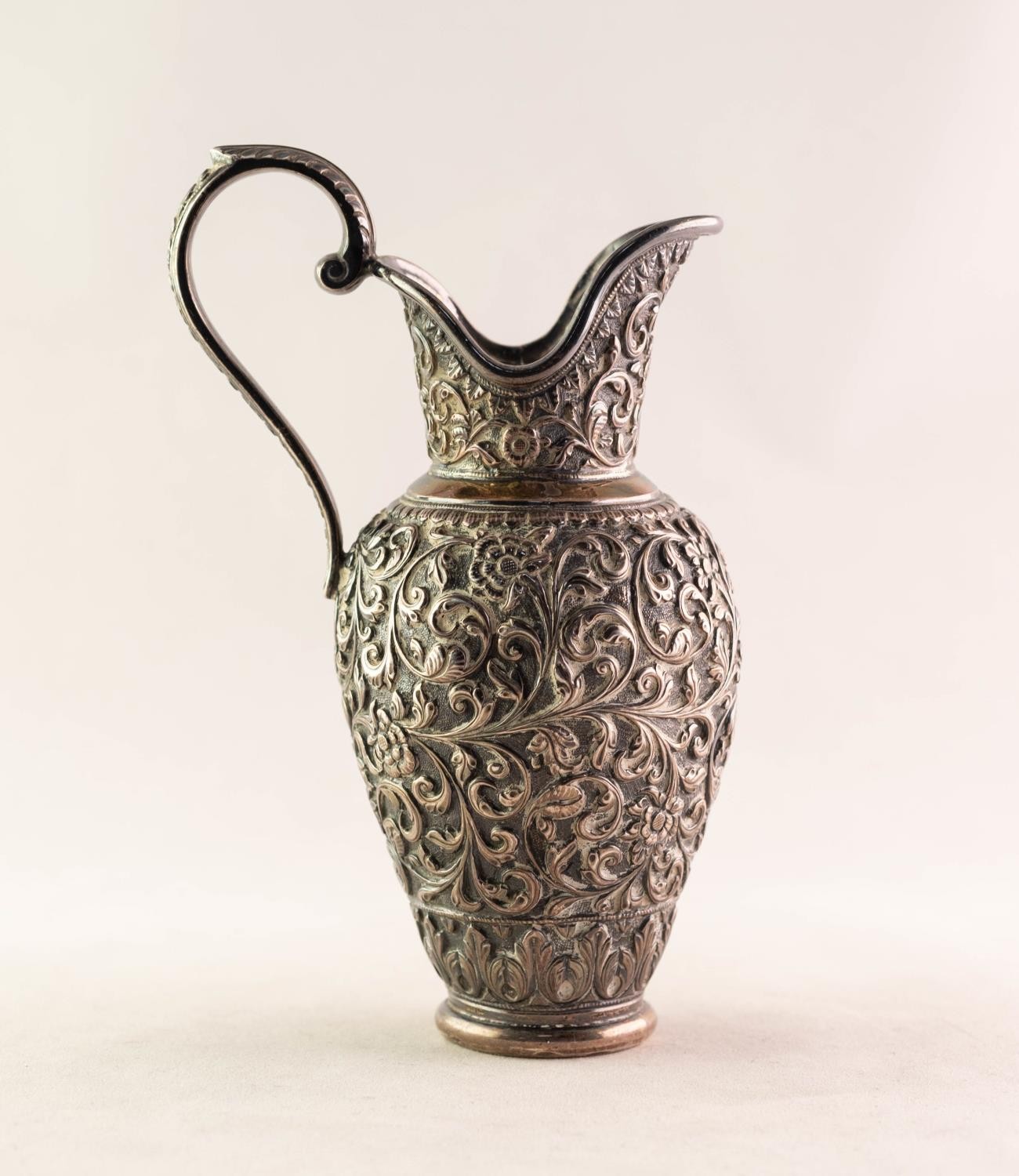 INDIAN SILVER COLOURED METAL URN SHAPED CREAM JUG, with raised C scroll handle with acanthus thumb