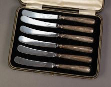 GEORGE V CASED SET OF SIX AFTERNOON TEA KNIVES WITH RAT TAIL PATTERN FILLED SILVER HANDLES,