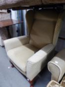 A WINGED BACK EASY ARMCHAIR, COVERED IN BEIGE FABRIC