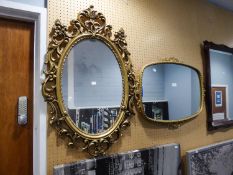 AN OVAL GILT FRAMED WALL MIRROR WITH SCROLL DECORATION AND ANOTHER WITH SCROLL DECORATION (2)