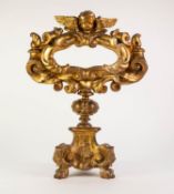 NINETEENTH CENTURY CARVED GILT WOOD PEDESTAL RELIQUARY, the oval aperture with scroll work frame and