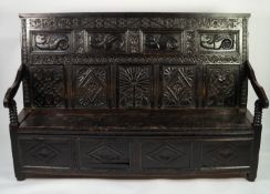 SEVENTEENTH CENTURY CARVED DARK OAK LARGE BOX SETTLE, the sloping back with four panels carved