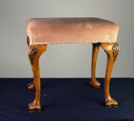 EARLY TWENTIETH CENTURY CARVED WALNUT STOOL, the oblong top covered in pink and floral fabric, and