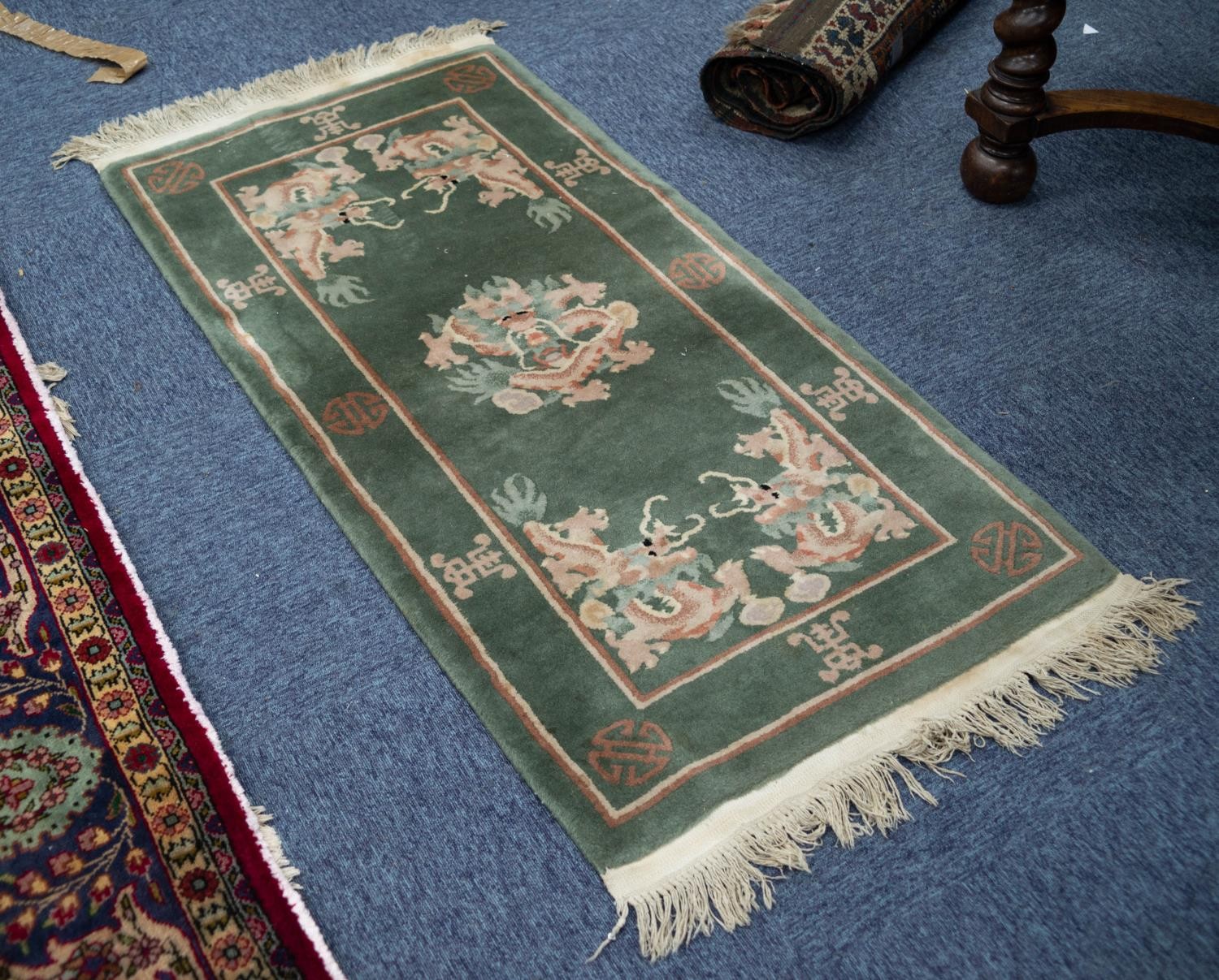 A WASHED CHINESE OBLONG RUG, with dragon medallion and spandrels on a moss green field, 4'6" x 2'4"