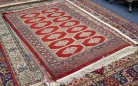PAKISTAN BOKHARA RUG, with two rows of primary guls on a crimson field divided by three rows of