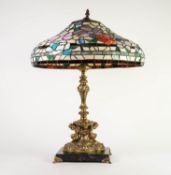 MODERN ROCOCO STYLE GILT METAL TABLE LAMP WITH TIFFANY STYLE SHADE, the lamp cast with a pair of