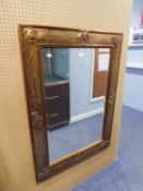 A RECTANGULAR BEVELLED EDGE WALL MIRROR, IN TEXTURED GILT FRAME, WITH EMBOSSED SHAPES, 3'8" HIGH,