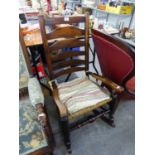 AN ANTIQUE ELM LADDER BACK ROCKING ARMCHAIR, WITH RUSH SEATS